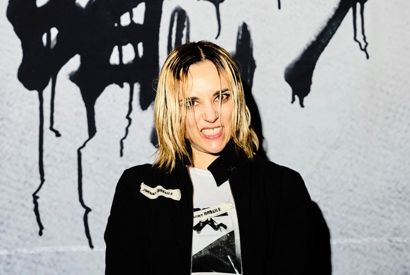 Jehnny Beth smiling infront of graffiti wall